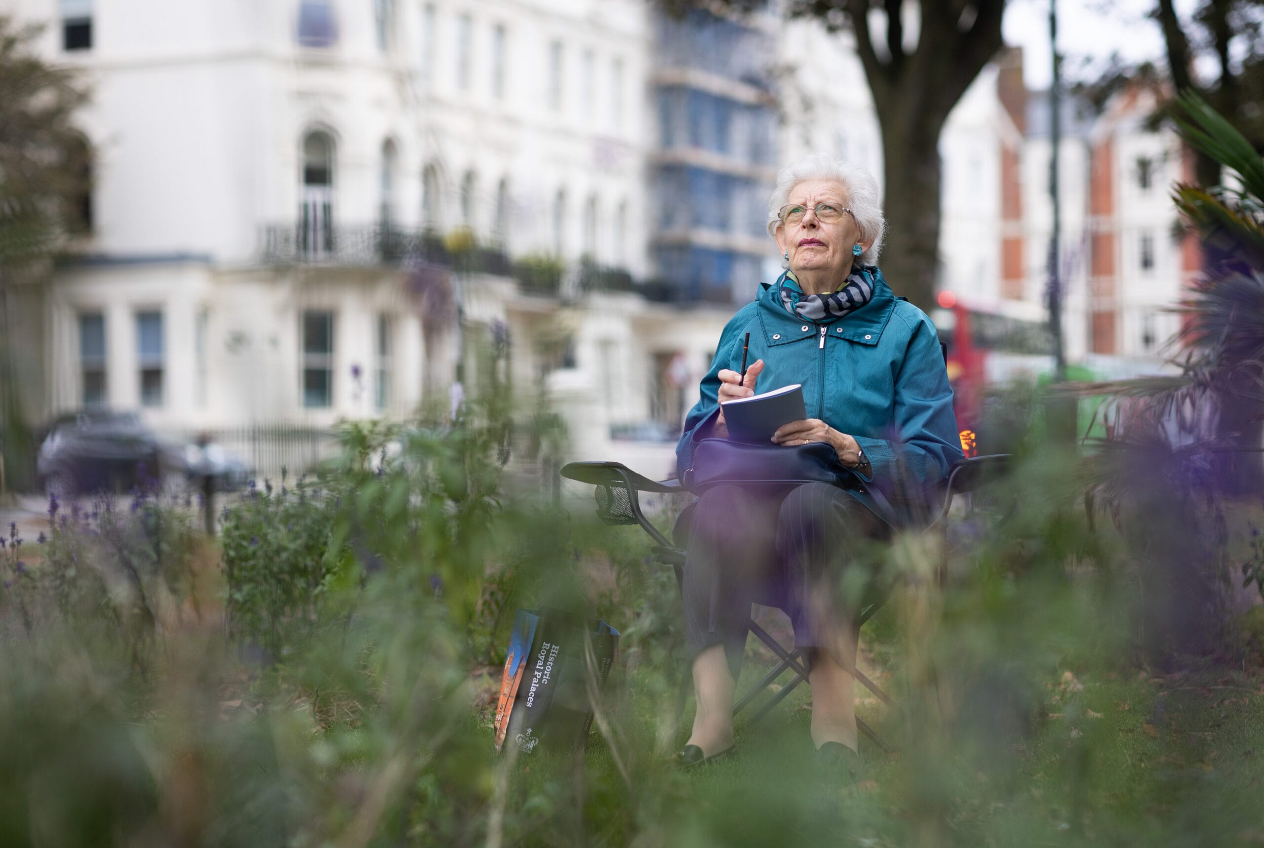 Mujer mayor sentada al aire libre reflexionando y tomando notas