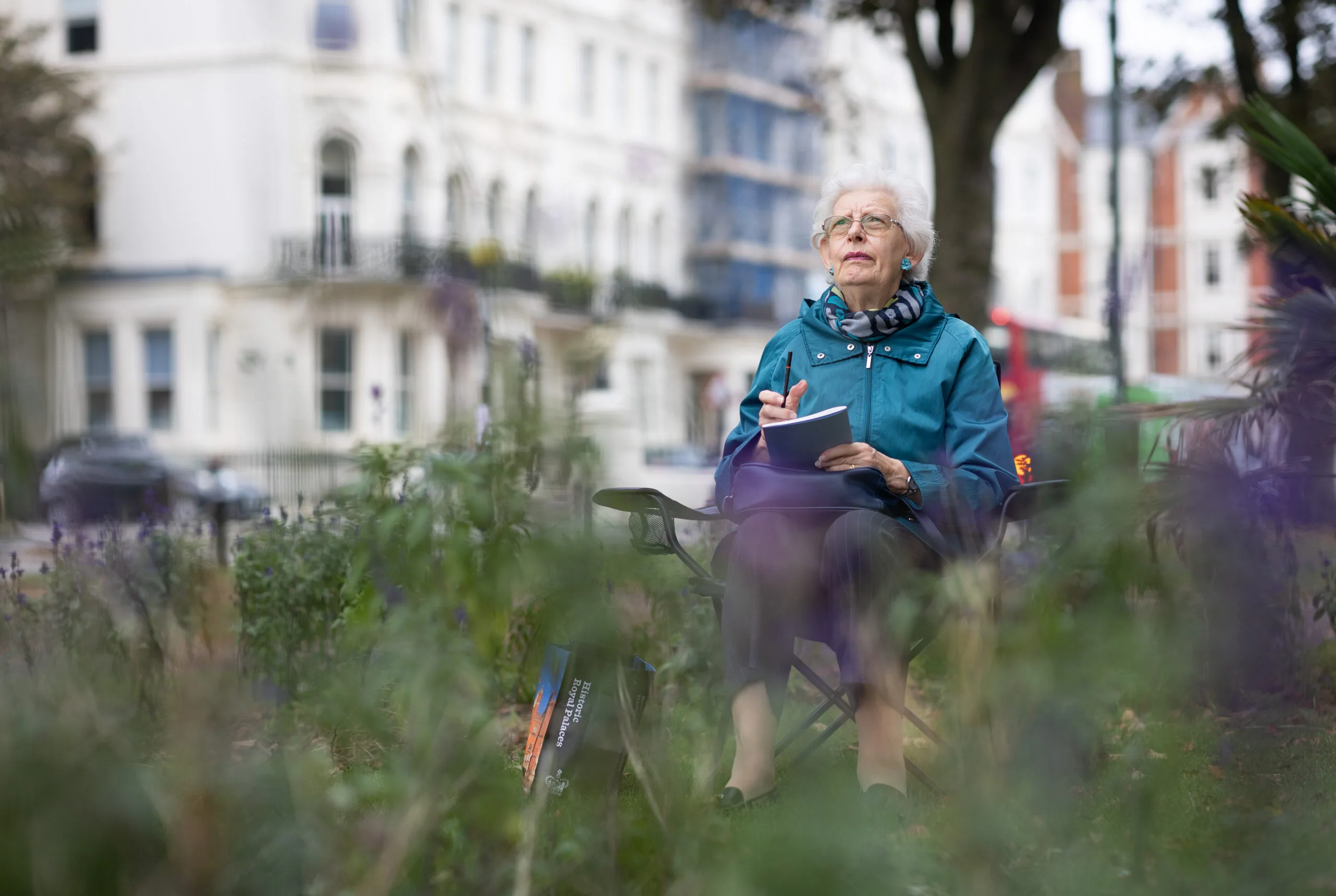Mujer mayor sentada al aire libre reflexionando y tomando notas